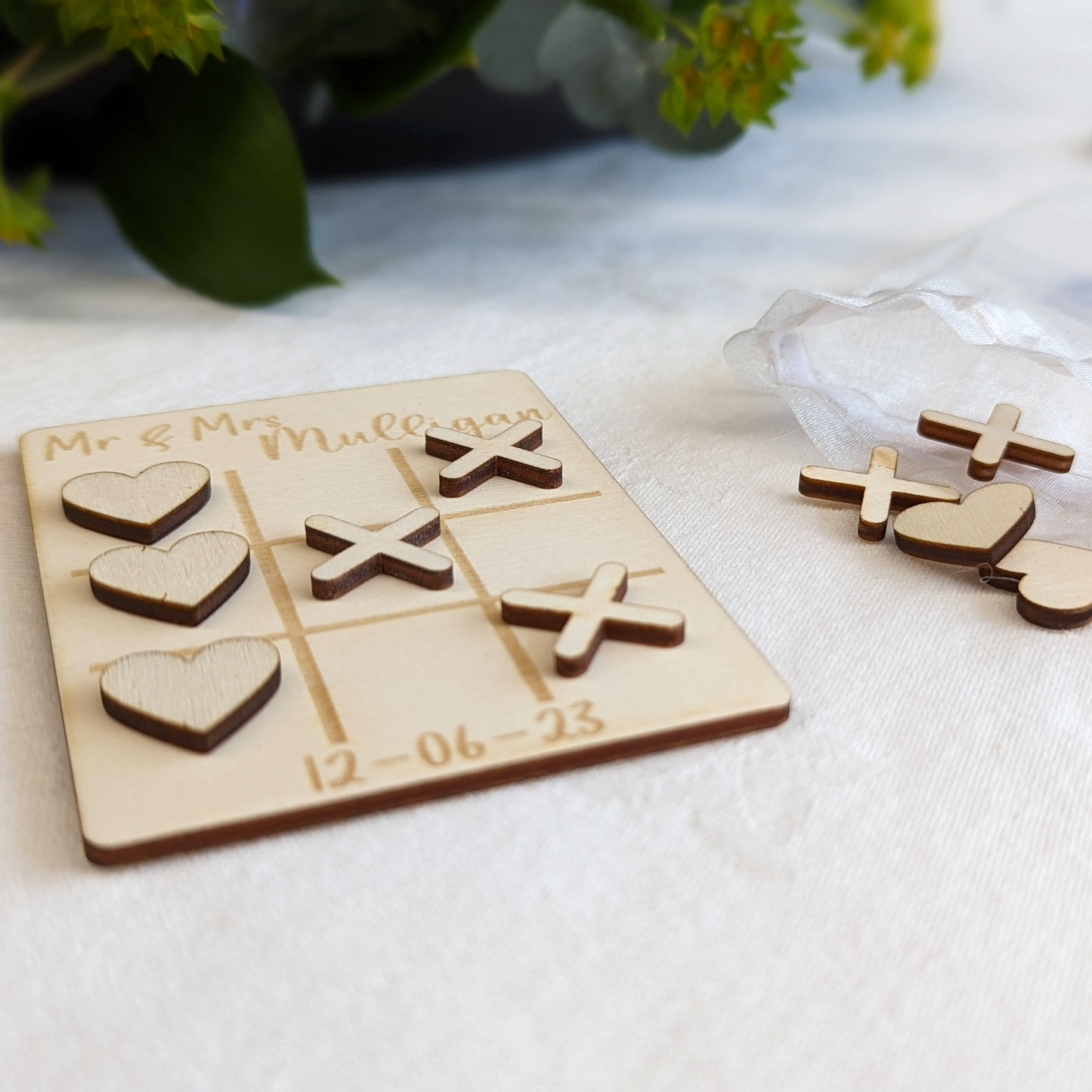 Personalised wooden wedding table game on a white table cloth at a wedding.