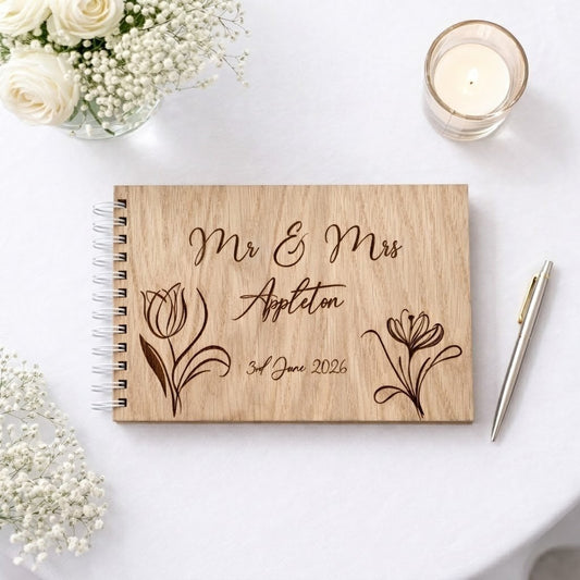 engraved guest book with floral design and mrs & mrs engraved into the wood on a wedding table.