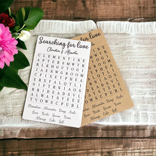 A close-up of a pair of wedding word search cards featuring the couple's names personalised at the top, with a clean grid of wedding-themed words