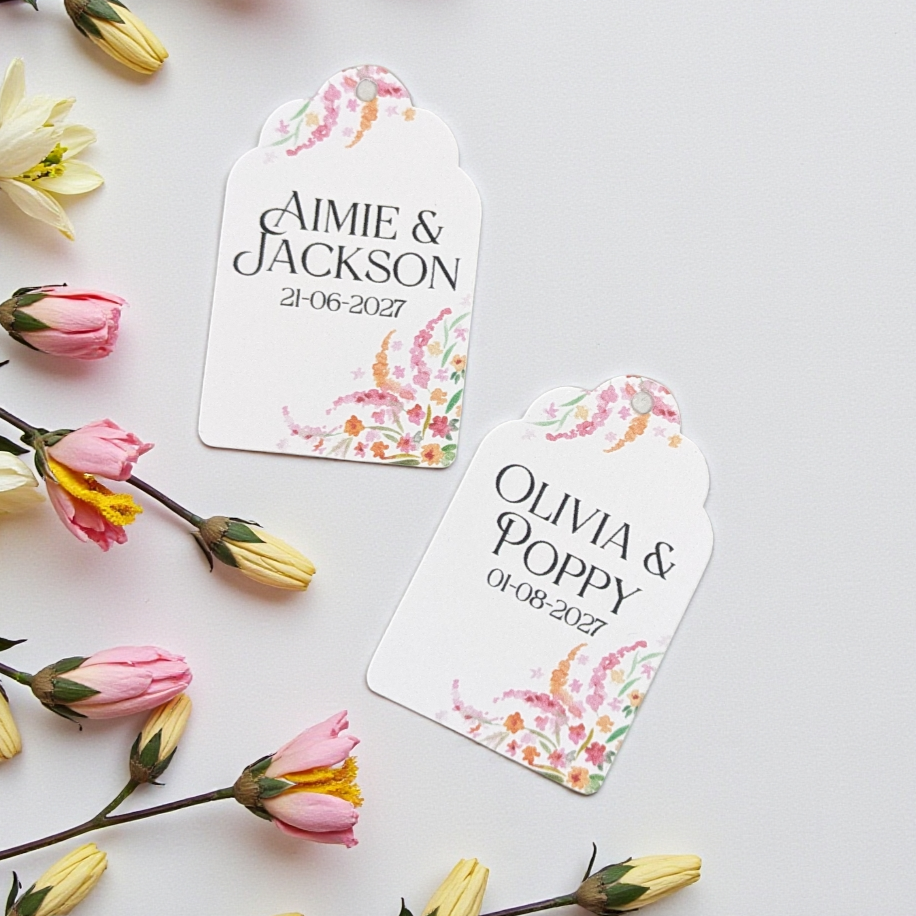 Custom romantic wedding favour labels featuring soft pastel flowers, perfect for a garden party or vintage-themed wedding reception. Tags lie flat on a white background with flowers adorning edges