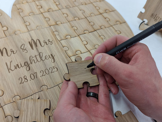 Close-up of a natural wood heart puzzle piece. The couple's names and wedding date laser-engraved into the central heart piece.