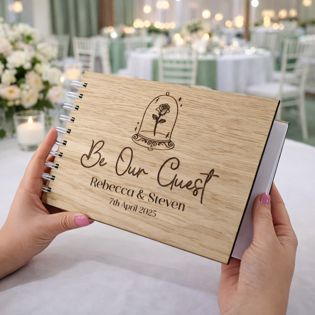 a wedding guest book alternative made from wood with the words 'Be our guest' and the couples names engraved in to the wooden guest book at a sage green themed wedding venue. 