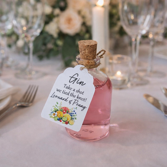 Small bottle of pink gin with a personalised tag for wedding wedding favours. On a wedding table.