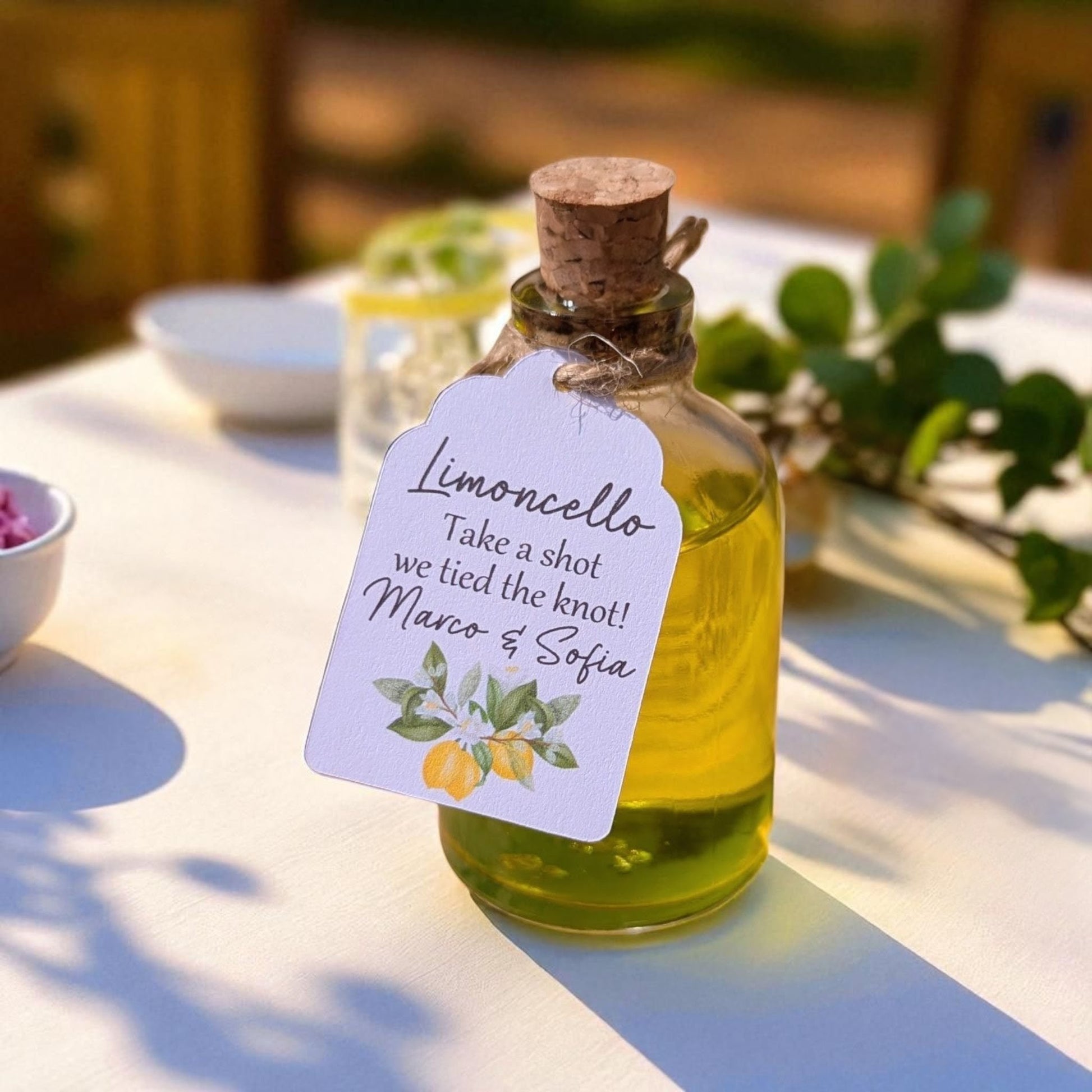 personalised limoncello wedding favour bottle with tag in the sunshine on a white tablecloth