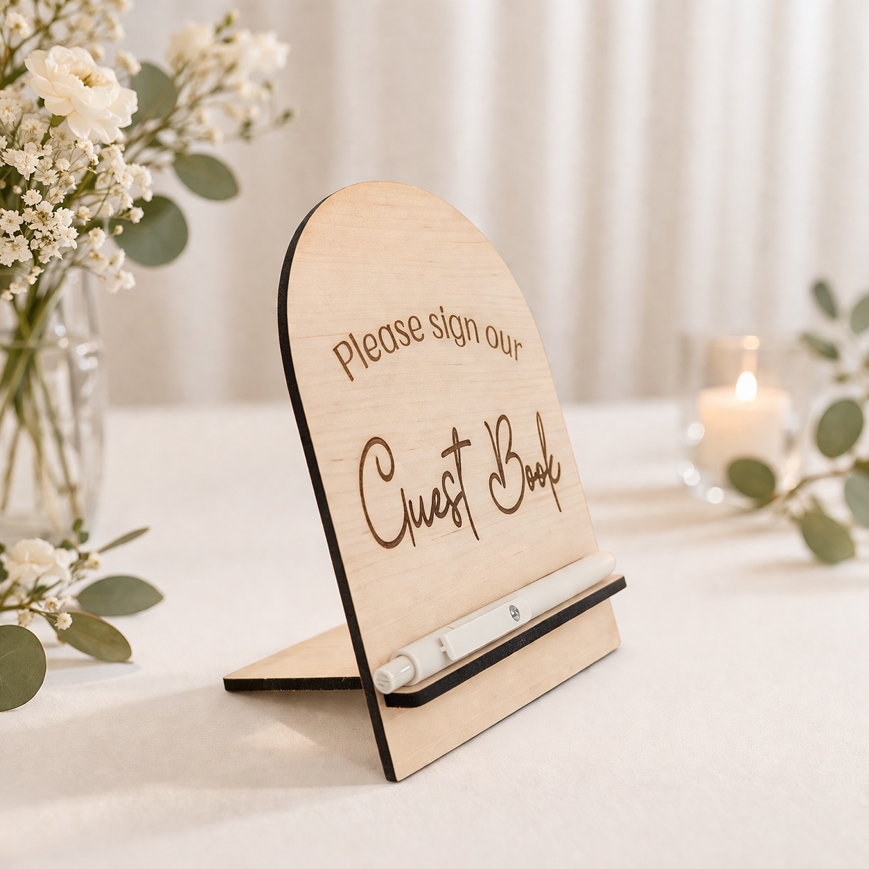 free standing wedding guest book sign on a white table with florals details in the corner